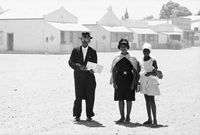 An elder of the Dutch Reformed Church walking home with his family after the Sunday service, Carnavon, Cape Province (Northern Cape), January 1968 by David Goldblatt contemporary artwork photography