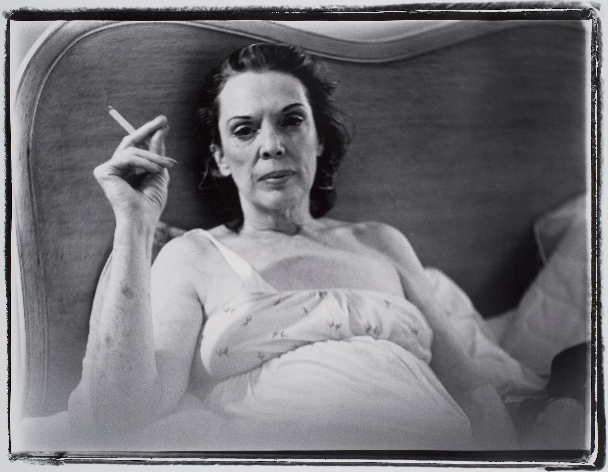 A gelatin silver print photograph of a mother holding a burning cigarette by Marilyn Minter, entitled Coral Ridge Towers (Mom Smoking) dated 1969