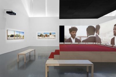Mónica de Miranda, South Circular (2019). Split-screen HD video, sound, wood, 4 speakers, red carpet, stairs benches. 22 min 57 sec. 410 x 466 x 243 cm. Exhibition view: __EDP Awards 2019, MAAT – Museum of Art, Architecture and Technology, Lisbon (19 March–19 August 2019).