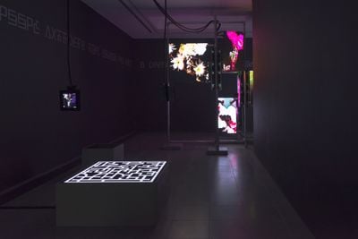 A dark room with multiple screen propped up in metal bars as a part artist Hito Steyerls's exhibition at the Serpentine Galleries in London