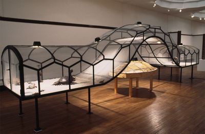 Huang Yong Ping, The Bridge (1995). Painted steel structure with mesh, wood, warming lamps, electric cable, found faux-bronze figurines (patinised and painted), snakes, and turtles. 320 x 1200 x 180 cm. Exhibition view: Galerie des 5 Continents, Musée National des Arts d'Afrique et d'Océanie, Paris (1996). © Huang Yong Ping.