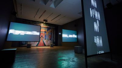 Three video installations showing blurred Arabic writing in front of painted mural