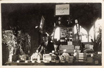 An archival photograph from 1924 shows a man behind a table upon which plants are placed at the Adana Agricultural Fair.