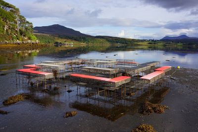 An installation of metal cage-like structures that form a matrix of seating is situated along the shores of a location in the Isle of Skye in Scotland, during low tide.