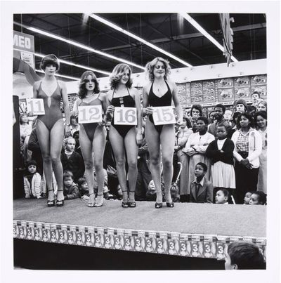 David Goldblatt, Saturday morning at the Hypermarket: semi-final of the Miss Lovely Legs Competition (1980). Gelatin silver hand print. 27.9 cm × 27.9 cm, image; 31.8 cm × 30.5 cm, paper. © The David Goldblatt Legacy Trust.