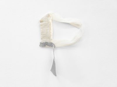 A fragmentary, subtle textile work by Hana Miletić in shades of grey and white hangs against a white wall.