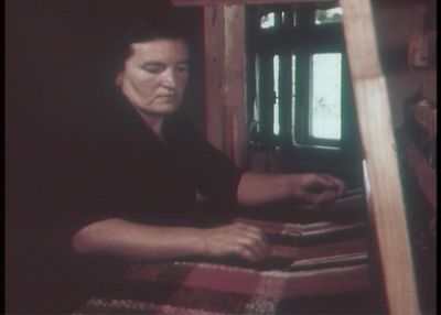 A grainy image of a woman captures her working at a loom.
