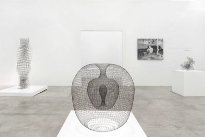 Three sculptures on exhibition fronting a monochrome  portrait photograph