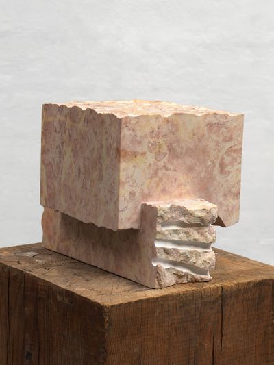 Pale pink marble sculpture with carved edges and uneven surface