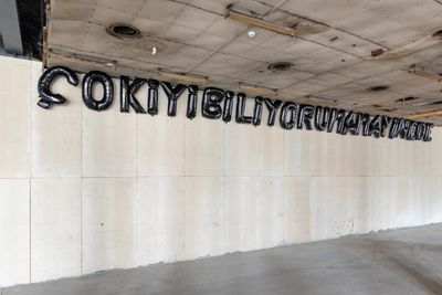 Wall installation showing letters made from 24 helium inflated mylar balloons.