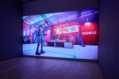 A large screen in the gallery space shows the artist Lu Yang as her alter ego Doku in a futuristic setting.