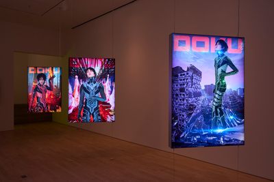 A series of three hanging screens in the gallery space show a figure in each in a futuristic landscape.