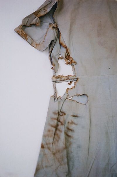 The left-hand side of a light blue blouse is photographed by Miyako Ishiuchi, highlighting holes and torn parts that run along its length.