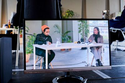 Amal Alhaag and Zippora Elders are pictures on a television screen that stands in an exhibition hall, in a seminar organised by de Appel.