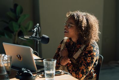 Jaleesa Clows sits behind a MacBook and a microphone in the production of a radio show at de Appel.
