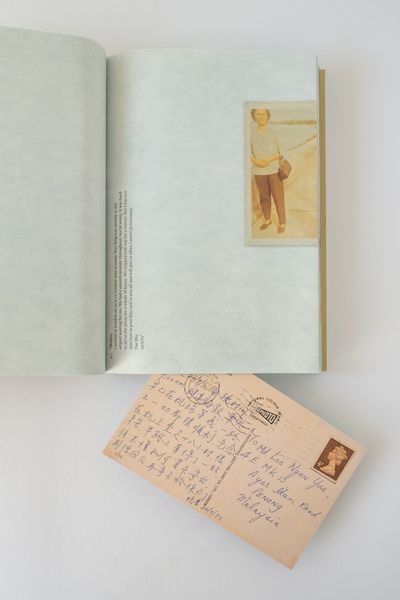 Open book showing a vertical photographs of a woman set above a postcard with Chinese text.