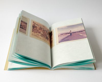 Open book showing coloured photographs printed across the pages. 