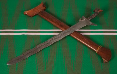 A kris sword from the Philippines with wavy blade, silver mounted hilt, and wooden pommel. 697 mm length. Donated in 1911.