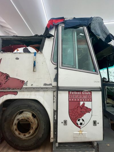 Marcin Dudek, NEOPLAN (2023). Disassembled NEOPLAN Dinamo FC bus, 6 TV screens, 6 DVD players, vintage T-shirt canopy and mixed media. 1200 x 240 x 340 cm.