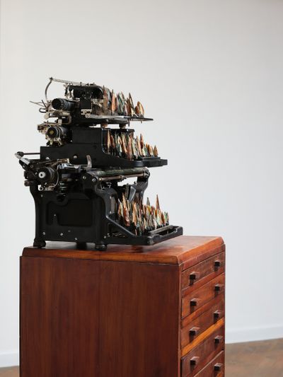 Zac Langdon-Pole, A Quiver of Names (2022). Wooden specimen cabinet drawers, Blickensderfer, Royal, and Underwood typewriters, keys replaced with mixed ancient arrowheads: Neolithic (c. 7000–1700 BCE); Ancient Greek (c. 1200 BCE–600 AD); Roman (c. 753 BC–1453 AD); Ottoman (c. 1400–1600 AD). 155 × 48.5 × 42.5 cm.