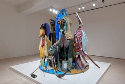 Daniel Lind-Ramos, Centinelas de la luna nueva (Sentinels of the New Moon) (2022–2023). Wood, metal pulley, metal, metal chairs, plastic, found textile, acrylic sheet, rope, metal mesh, shovel, tape, metal fasteners, wire, drum, shovel, found pots, tarp, dried coconut inflorescence, machete, tripod, electric fan parts, wood crab trap, cardboard mask, welding mask, dried and lacquered coconuts, boxing bag, metal drum, metal box, clamps, concrete, metal construction hardware, metal hoe, five gallon PVC bucket, wood base, mirror, glass, and pitchfork. 274.3 × 254 × 254 cm. Exhibition view: El Viejo Griot — Una historia de todos nosotros (The Elder Storyteller—A Story of All of Us), MoMA PS1, New York (20 April–4 September 2023).
