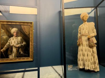 Left to right: Joshua Reynolds, Portrait of Captain John Foote (1761–1765); embroidered muslin jama, shawl, and patka worn by Foote in the painting. Exhibition view: India in Fashion: The Impact of Indian Dress and Textiles on the Fashionable Imagination