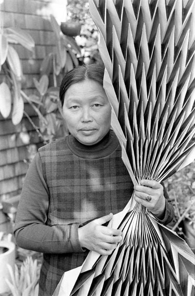 Laurence Cuneo, Ruth Asawa holding a paperfold (c. 1970s). Gelatin silver print. 24.9 × 18.6 cm. Department of Special Collections, Stanford University Libraries. Photo © Laurence Cuneo. Artwork © 2023 Ruth Asawa Lanier, Inc. / Artist Rights Society, New York.