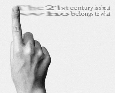In shades of grey, a hand with a pointed index finger swipes the words 'The 21st century is about who belongs to what', which gradually fade out.