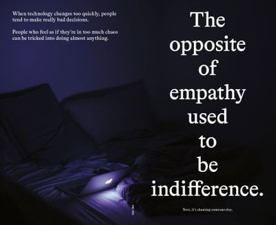 A darkened room shows a computer on a bed, the screen lighting up the space, and to the right a phrase reads: 'The opposite of empathy is no longer indifference. Now, it's shaming someone else.'