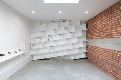 A slanted shelf against the far wall supports a series of books.