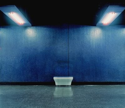 A blue-tiled wall features a lonely stool positioned in front of it in an underground station in Hong Kong.