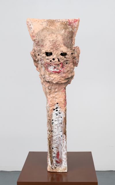A fleshy pink sculpture by Huma Bhabha featuring the head of a distorted figure atop an elongated neck.