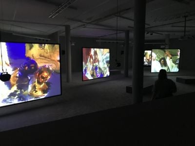 Three video installation screens showing saturated human figures.
