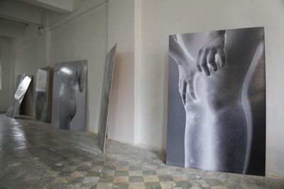 Large screen printed film negative on gallery floor show naked bodies from the back