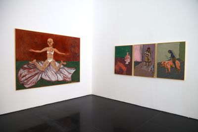 Two white walls in the gallery space feature on the one side, a large canvas encompassing a figure sitting on the floor with their legs splayed against a red background, and three paintings in a line to the right featuring pigs, roosters, and figures engaged in ambiguous activities.
