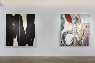 Two abstract paintings by Manuel Mathieu hanging in the gallery space, one black and white and the other in pink, yellow, green, and white hues, which come together to resemble a figure.