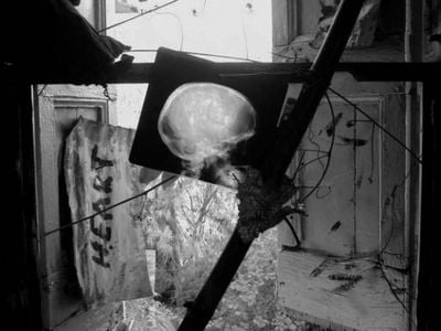 A black and white photography of an early installation by Manuel Mathieu with graffiti on the wall and an X-ray scan of a head, light from the window behind it shining through.