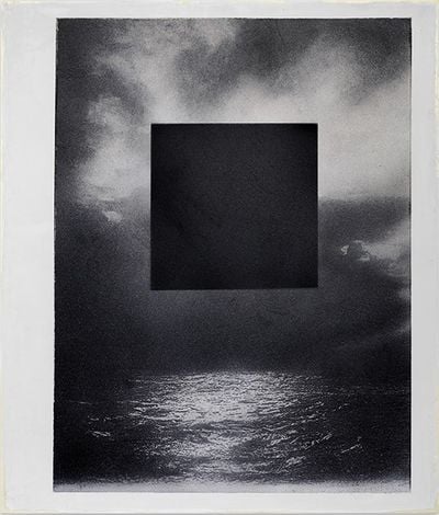 A grainy, black and white image of the ocean beneath a cloudy sky is overlaid with a large black square, in a mixed media work by Marco Tirelli.