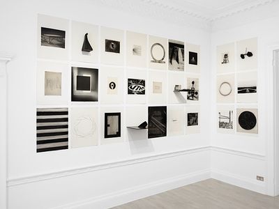 Two walls in a white gallery space are filled with black and white geometric imagery in varying sizes by Marco Tirelli.
