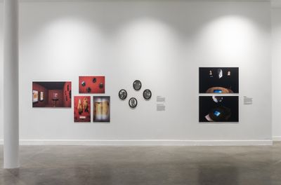 Photographic works of early installations by Michael Richards are lined up along a white wall in the exhibition space.