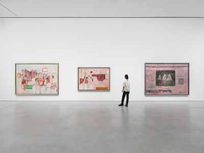 Three large paintings by Philip Guston feature klansmen and mechanic elements in hues of red, pink, and white.