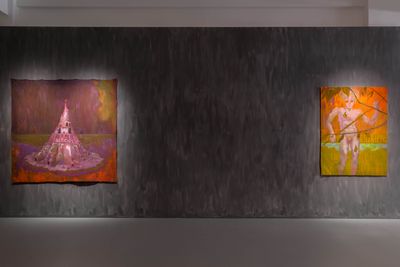 A painting of a burnt Tower of Babel in pink tones sits alongside a painting of a purple-tinted figure standing against a yellow and orange-hued landscape.