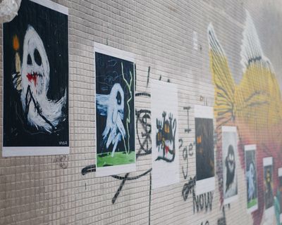A street in Hong Kong features an outdoor exhibition of images of ghosts printed onto paper and stuck to the wall.