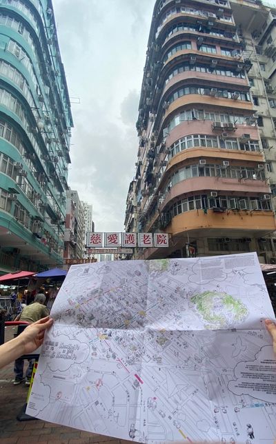 A map is held out beneath typical Hong Kong buildings from the 1980s in the city's Sham Shui Po district.