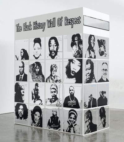 A large rectangular structure by Lauren Halsey is freestanding in the gallery space. It reads 'Black History Wall of Fame' and features mirrored portraits of individuals such as Octavia E. Butler and Lauryn Hill.