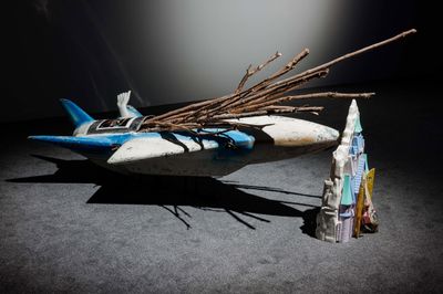 Sophie Jung, The Beckoning (jet str appear to be bloked stoked by the hir achery of might not leave not fell us loaded) (2023). Fibreglass and chrome funfair ride, frozen castle, jedi starfighter, clenched fist, sudden-branch-drop black forest pine wood, c-print ‘Schafegg’ text.