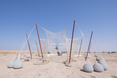 Ernesto Neto, SlugTurtle, TemplEarth (2022). Steel, recycled polyester crochet net, glazed ceramic globe, wooden posts, rubber balls, cotton fabric and wadding, dry grass, clove, plants 302 x 1784 x 2342 cm.
