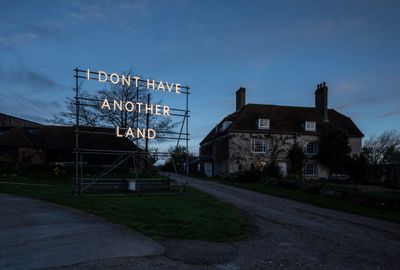 Nathan Coley, I DONT HAVE ANOTHER LAND (2022). Illuminated text on scaffolding. 5.3 x 5.3 x 2.5m. Installation, Charleston, Firle.