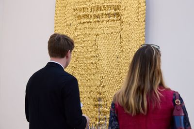 Fair goers examine Olga de Amaral’s Viento Oro (2014). Linen, gesso, acrylic, Japanese paper, and gold leaf. 225 x 120 cm.
