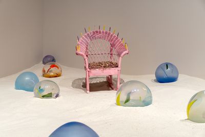 Pink chair on white sand surrounded by eight glass spheres